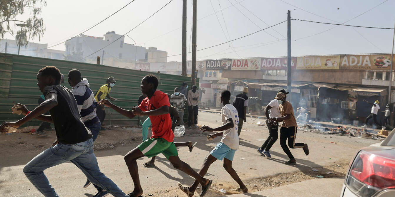 Senegalese demonstrators run away during clashes with riot police as they protest against the postponement of the Feb. 25 presidential election, in Dakar